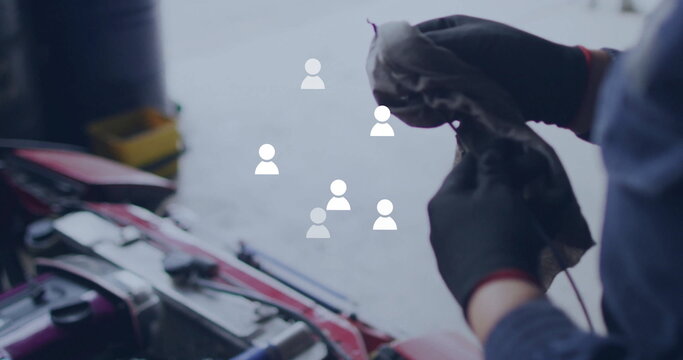 Fototapeta Cleaning mechanic wiping engine in garage, with rag by red car hood, tool bin, copy space