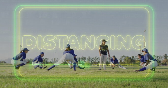 Stretching softball players wearing jerseys and baseball caps on field, with neon DISTANCING text - Powered by Adobe
