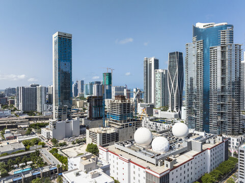 Aerial view of gleaming skyscrapers pierce the clear sky, reflecting sunlight amidst the urban landscape of Miami's modern architecture, Miami, Florida, United States.