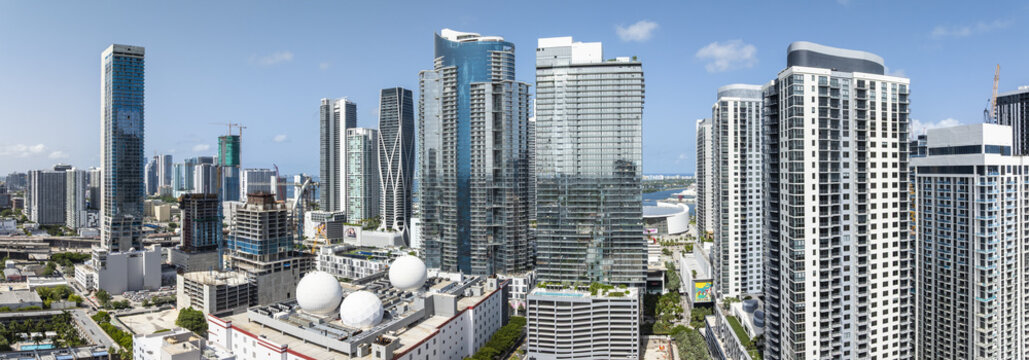 Aerial view of gleaming skyscrapers rise against the bright skyline, reflecting the clear blue skies over the FTX Arena, Miami, Florida, United States.
