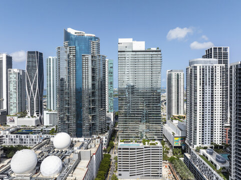Aerial view of gleaming skyscrapers pierce the skyline, reflecting the clear blue sky above the vibrant city, Miami, Florida, United States.