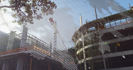 Rising concrete frame at urban site, with scaffolding, cranes, tree branch and map overlay