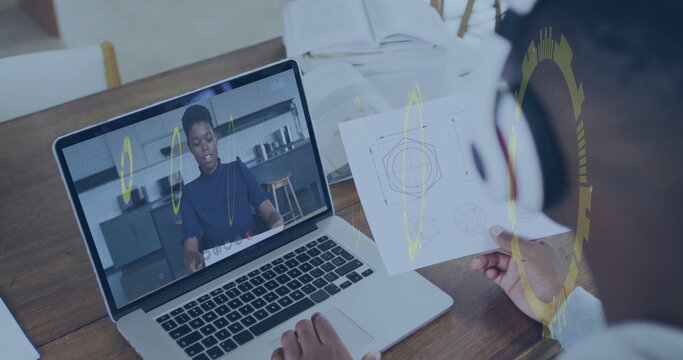 Comparing student holding printed diagram at wooden desk with remote lesson on laptop, copy space - Powered by Adobe
