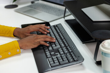 African American man sitting at white desk in home office typing on black wireless keyboard