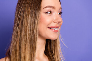 Smiling and charming young woman with braces on purple background showcasing joy and carefree style