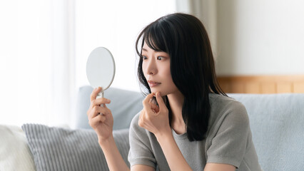 鏡で肌をチェックする女性