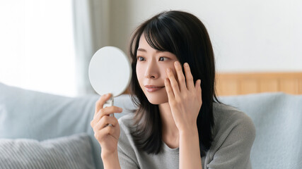 鏡で肌をチェックする女性