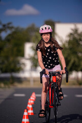 Young Girl Riding Bike Through Traffic Cones on Sunny Day