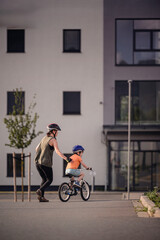 Adult Teaching Young Child to Ride Bicycle on City Street