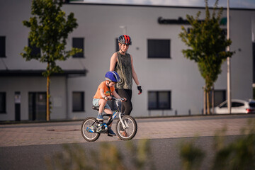 Adult Teaching Young Child to Ride Bicycle on City Street