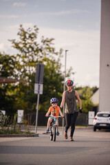 Adult Teaching Young Child to Ride Bicycle on City Street