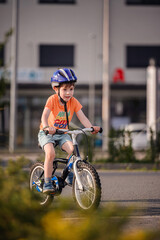 Fototapeta premium Happy Young Boy Riding Bicycle on Sunny Urban Street