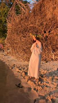 Ukrainian girl in wreath poses near water.

