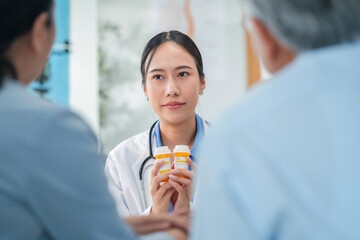 Asian doctor in uniform attentively assists a senior couple with medical paperwork in a hospital...