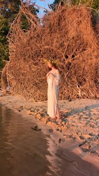 Ukrainian girl in wreath poses near water.
