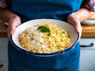 Woman holding plate with Risotto alla Milanese. Milanese style risotto - saffron risotto in hands, close-up