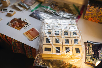 Vintage photo slides stored in plastic sheets with old prints on table