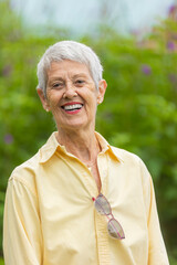 Happy senior woman with glasses on shirt smiling outdoors