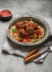 Delicious spaghetti with meatballs and tomato sauce on a rustic table with neatly arranged cutlery...