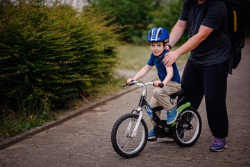 Parent Teaching Young Child to Ride Bike on Sidewalk
