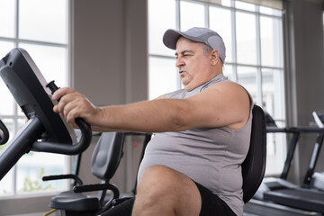 Man exercise bike in gym. Mature male workout biking in gym. Exercising legs. Fitness, gym and exercising
