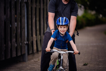 Parent Teaching Young Child to Ride Bike on Sidewalk
