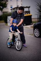 Parent Teaching Young Child to Ride Bike on Sidewalk