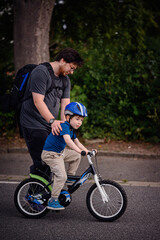 Parent Teaching Young Child to Ride Bike on Sidewalk