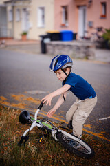 Young Boy Picking Up Fallen Bicycle on Side of Street © Иванна Емельянова