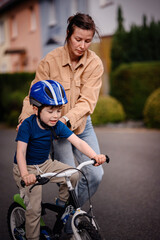 Mother Helping Son Learn to Ride a Bike Outdoors