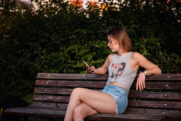 Woman Sitting on Bench Using Smartphone in Summer