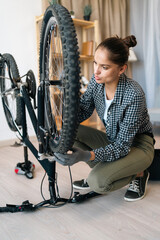 Bike broken problem. young woman repairing a bicycle wheel at home