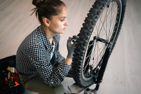Bicycle repair at home. Female cyclist servicing and repairing bicycle at home
