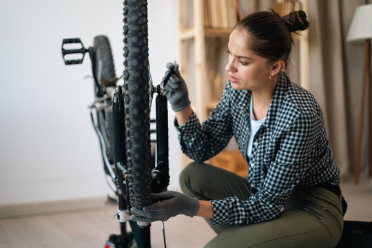 bicycle maintenance and repair. Woman in shirt pedals repairing bicycle in living room