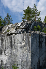 A marble cliff with pine trees on top in the Ruskeala Mountain Park in Karelia