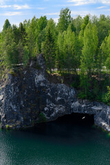 Lake at the bottom of a deep marble canyon with pine trees on top in the Ruskeala Mountain Park in Karelia