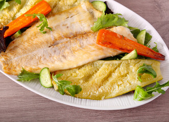 Baked white fish fillet with vegetables on plate