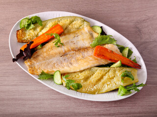 Baked white fish fillet with vegetables on plate