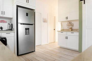 Stainless steel refrigerator with water dispenser highlighting white cabinetry and wood tone...