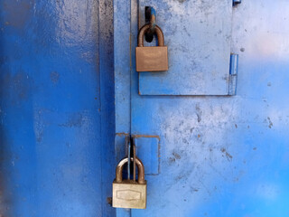 Two padlock on the blue iron door. Industrial with master key lock door.