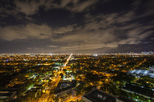 Fototapeta Aerial view of a vibrant city bathed in golden lights under a cloudy night sky, Miami, Florida, United States.