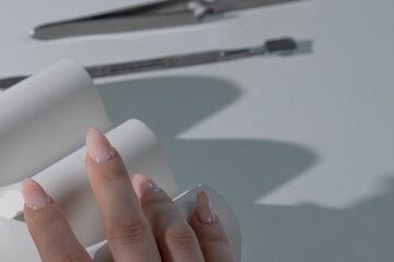 Sophisticated light manicure on delicate hand, beauty salon atmosphere with luxury tools