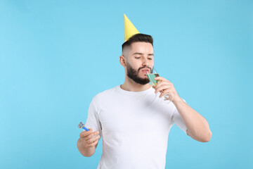 Happy Birthday. Handsome man with party hat, blower and glass of champagne on light blue background