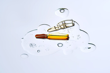 Two ampoules in a drop of cosmetic preparation. View from below.