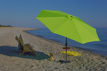 A bright mint beach umbrella, sun lounger and matching towel stand out on a deserted Adriatic beach. The lack of people creates a calming, almost surreal atmosphere of solitude and serenity by the sea