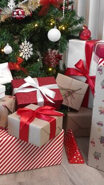 Vertical Gift boxes under a contemporary Christmas tree in a home with a white background, adorned with holiday Xmas ornaments, create a festive atmosphere for New Year decor. 