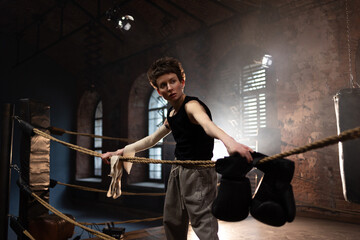 A woman in a boxing ring, wrapping an elastic bandage around her arms, preparing for boxing...