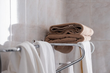There is a towel rack on the wall. The towels are white and brown