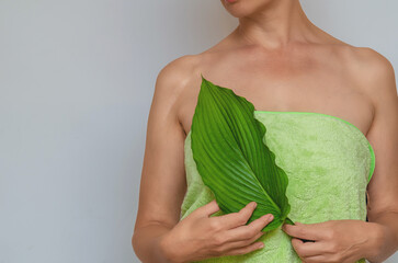Woman's bare shoulder and green leaf indicating scar. Sexy female body with scar.