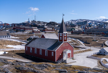 Snow covered pathway leads to traditional red wooden building of Church of our Saviour in Nuuk in Greenland